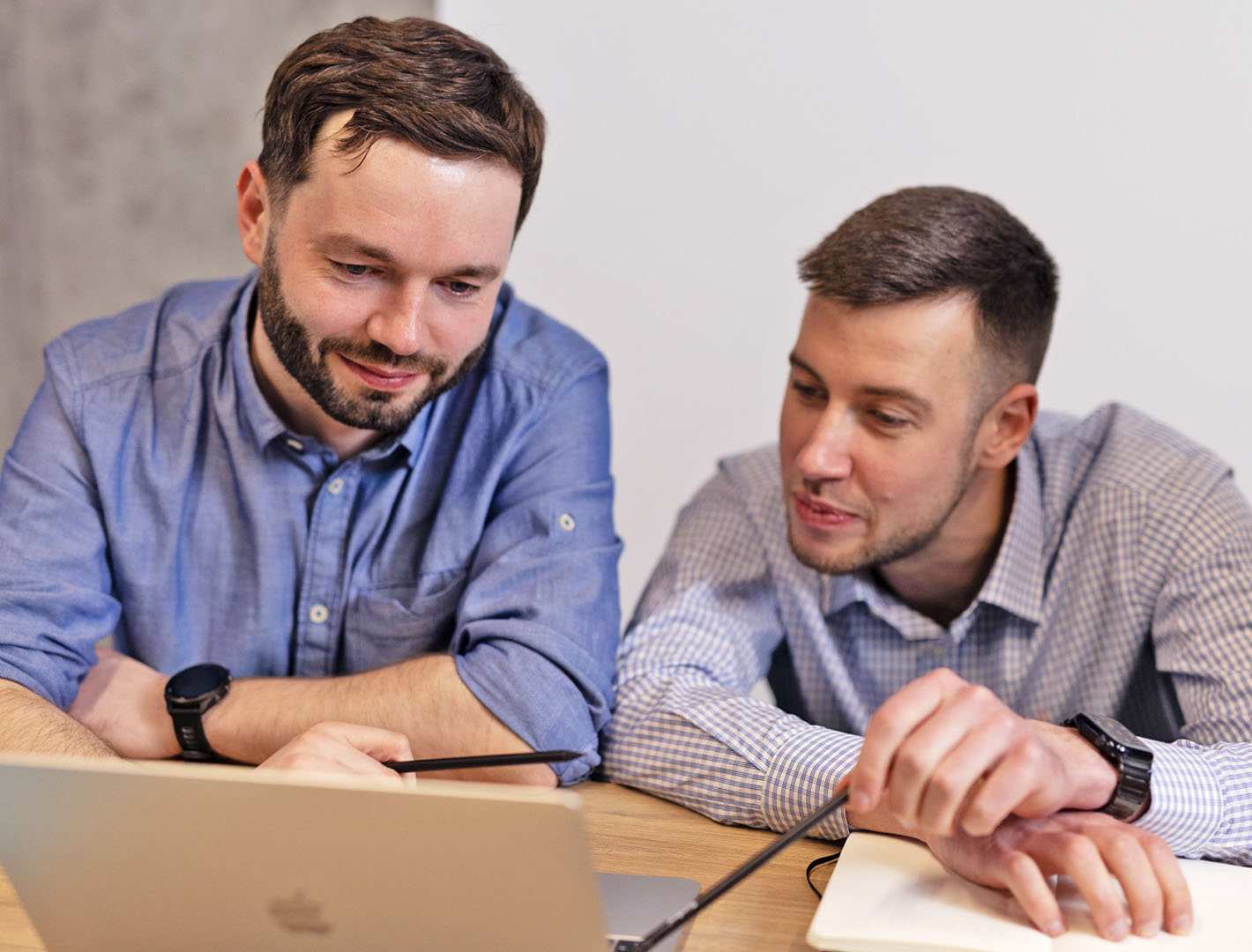 Two software professionals analyzing project performance data on a laptop.