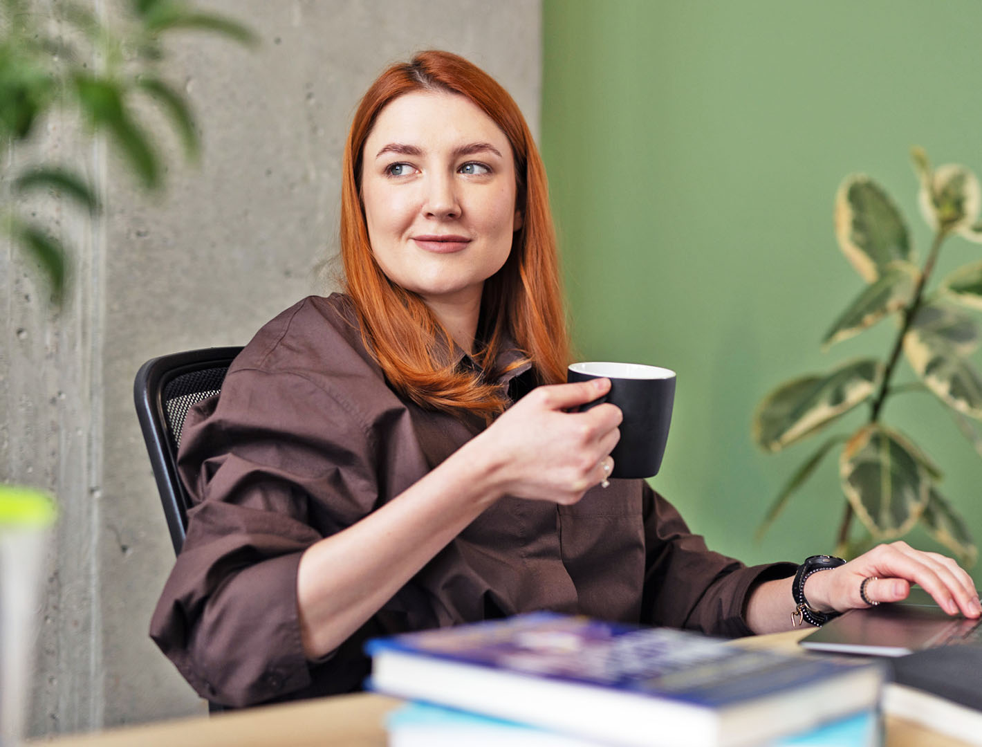 Confident businesswoman at desk reviewing company metrics with a cup of coffee.
