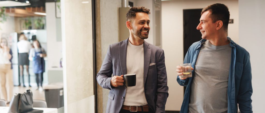 Two Sombra colleagues chatting over coffee in a modern office lounge, reflecting a friendly workplace culture.