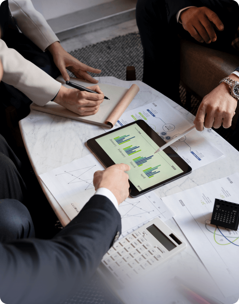 Business team reviewing financial data on a tablet dashboard alongside paper-based investment reports.