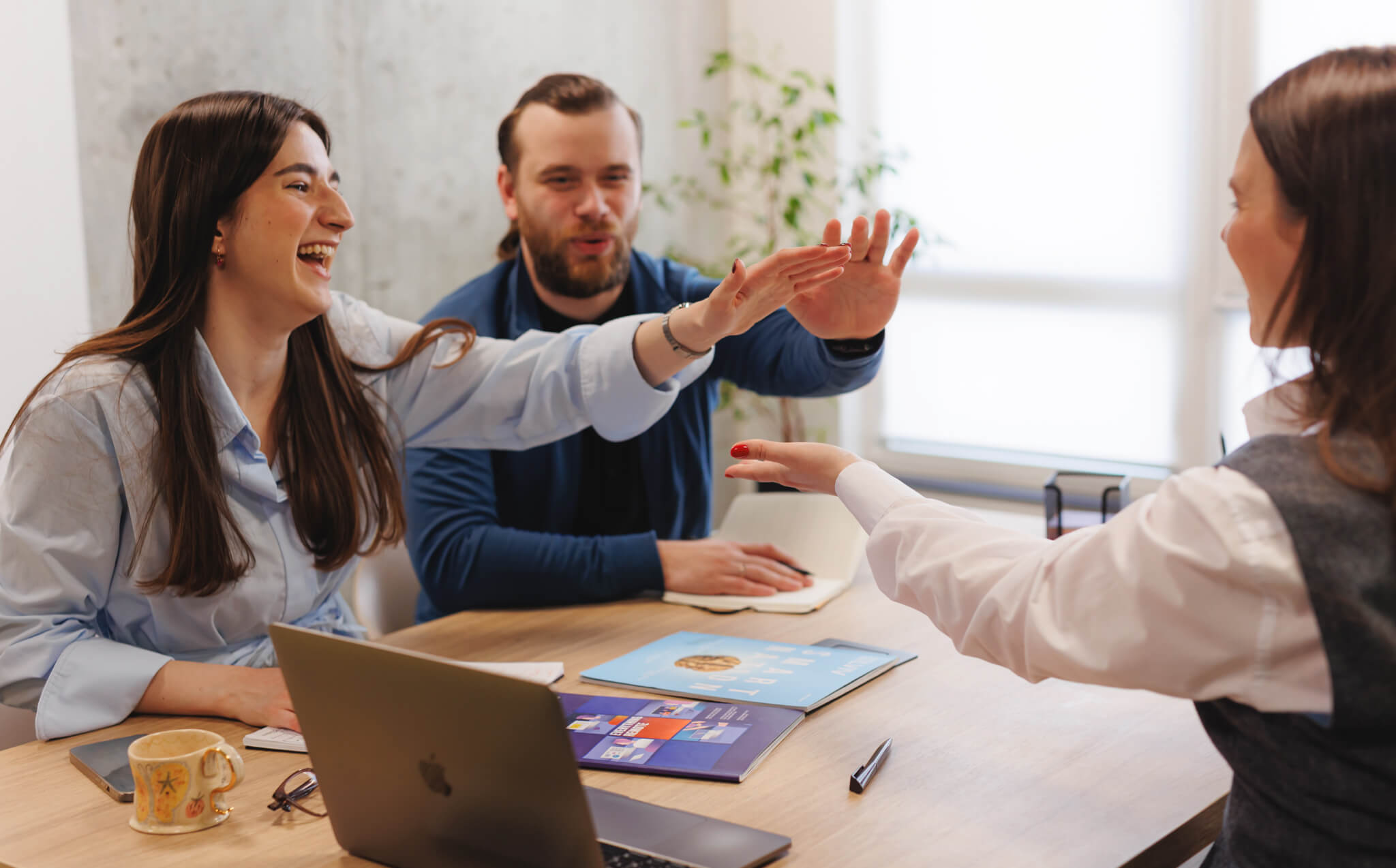 Team members exchanging high-fives in a bright meeting room, symbolizing proactive collaboration and initiative.